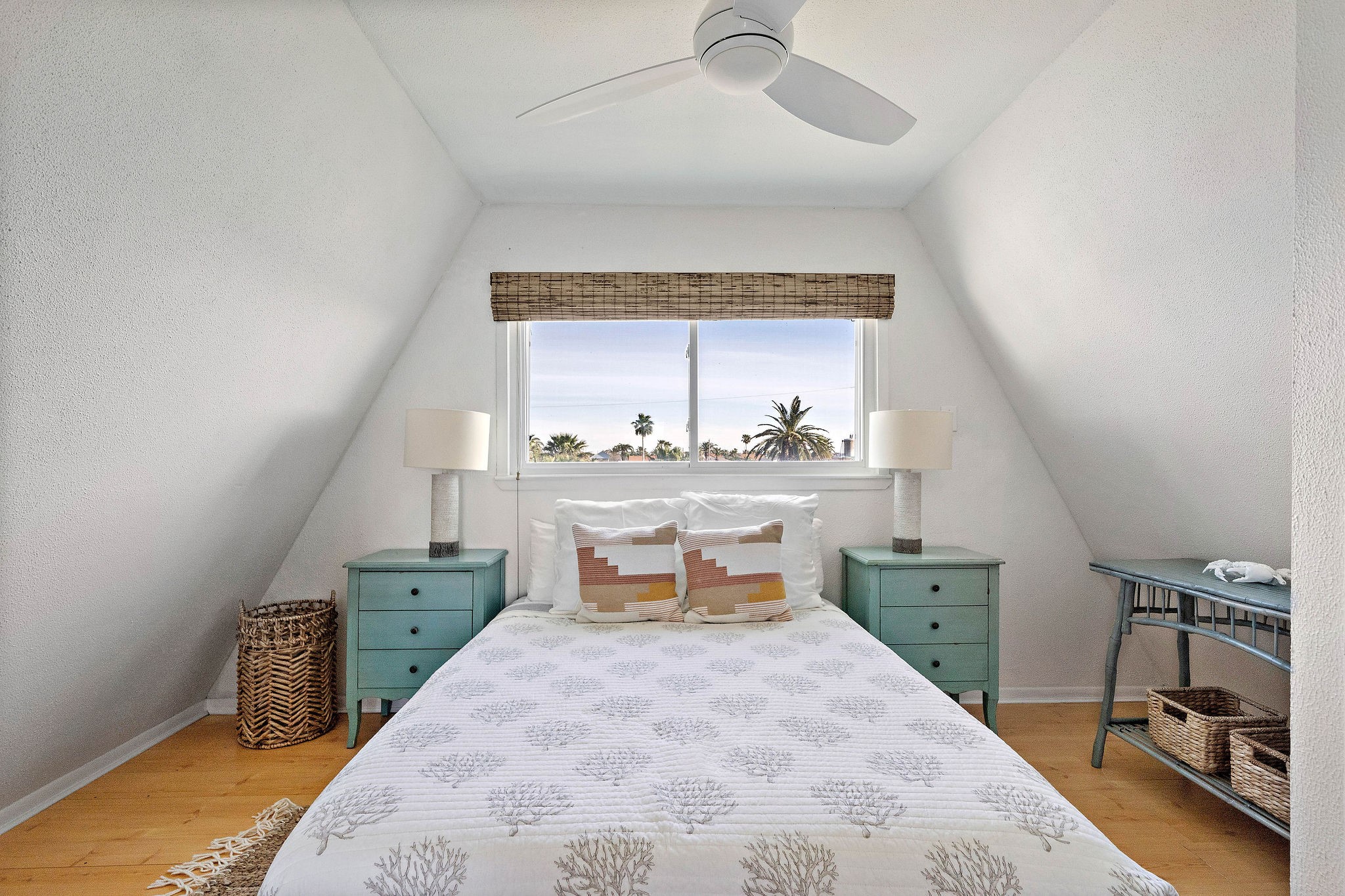 Charming bedroom with a cozy A-frame design, featuring a large window offering scenic views, complemented by soft, natural light and tasteful furnishings.