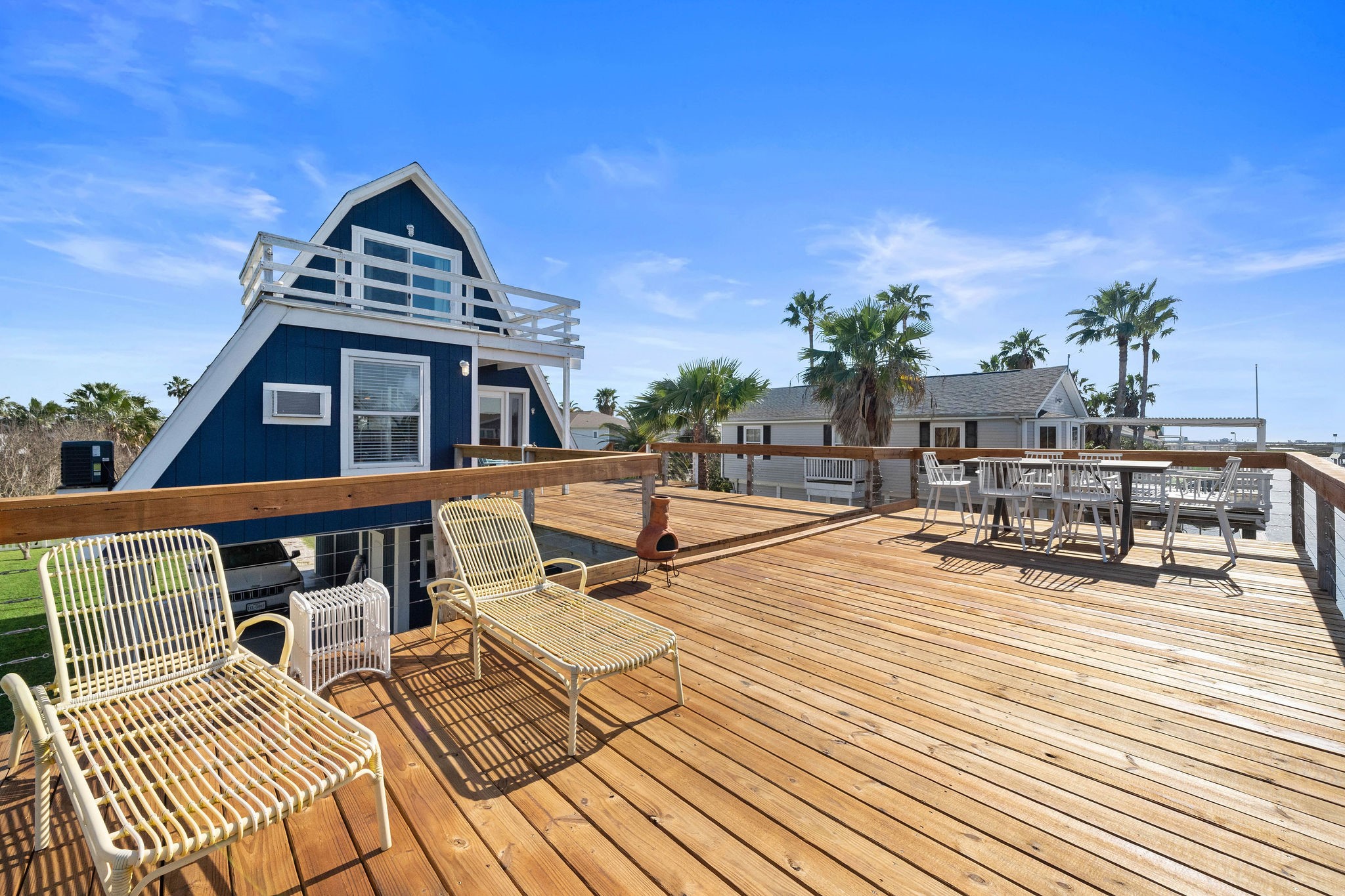 Charming A-frame home with a spacious wooden deck, perfect for outdoor relaxation and entertaining, surrounded by lush palm trees. Charming A-frame home with a spacious wooden deck, perfect for outdoor relaxation and entertaining, surrounded by lush palm trees.