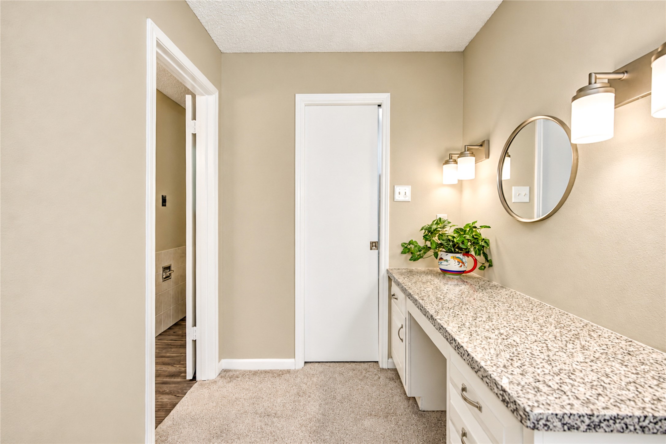Elegant hallway with a sleek granite countertop, modern lighting, and a stylish round mirror, offering a functional and inviting space.