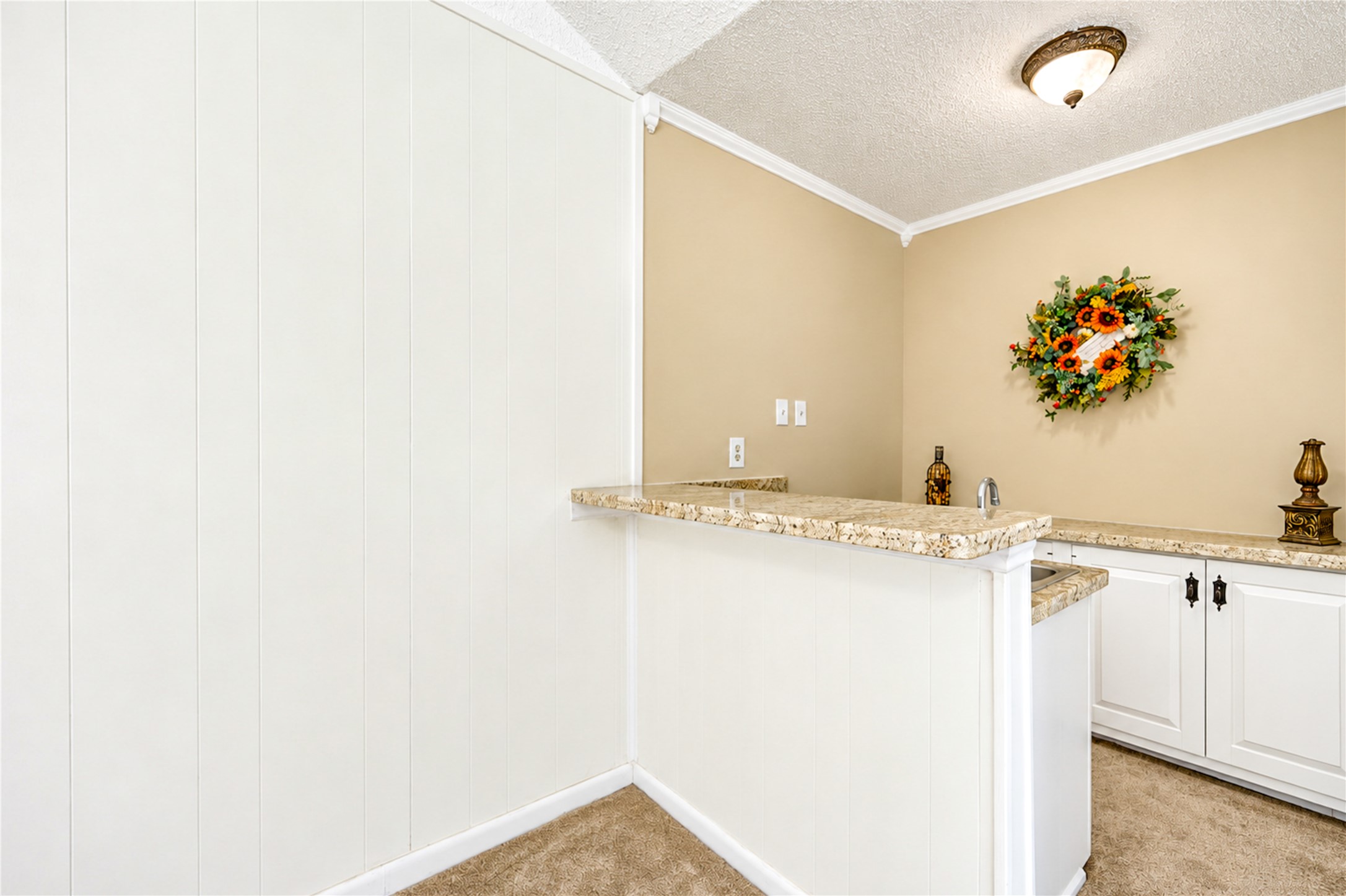 Charming nook with a cozy bar area, featuring elegant granite countertops, bright cabinetry, and tasteful decor, ideal for entertaining.