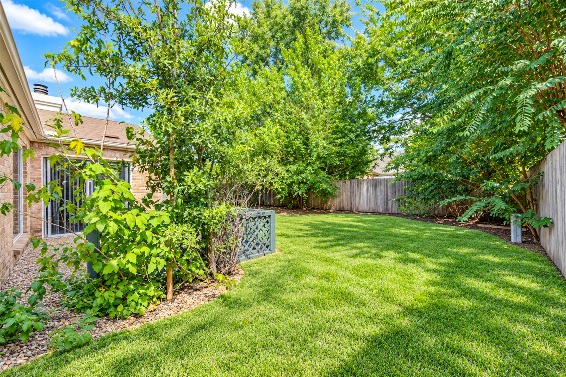 Lush green backyard with mature trees offers privacy and a serene outdoor space, perfect for relaxation and entertaining.