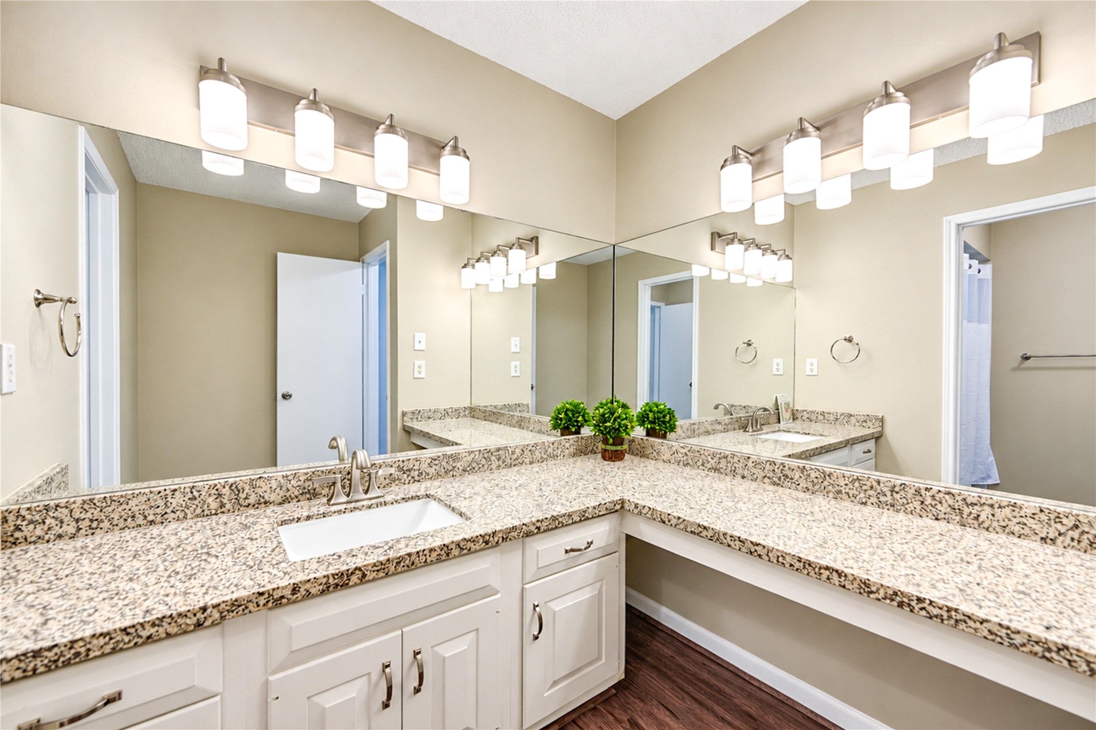 Spacious bathroom featuring dual sinks with elegant granite countertops, ample under-sink storage, and bright vanity lighting.