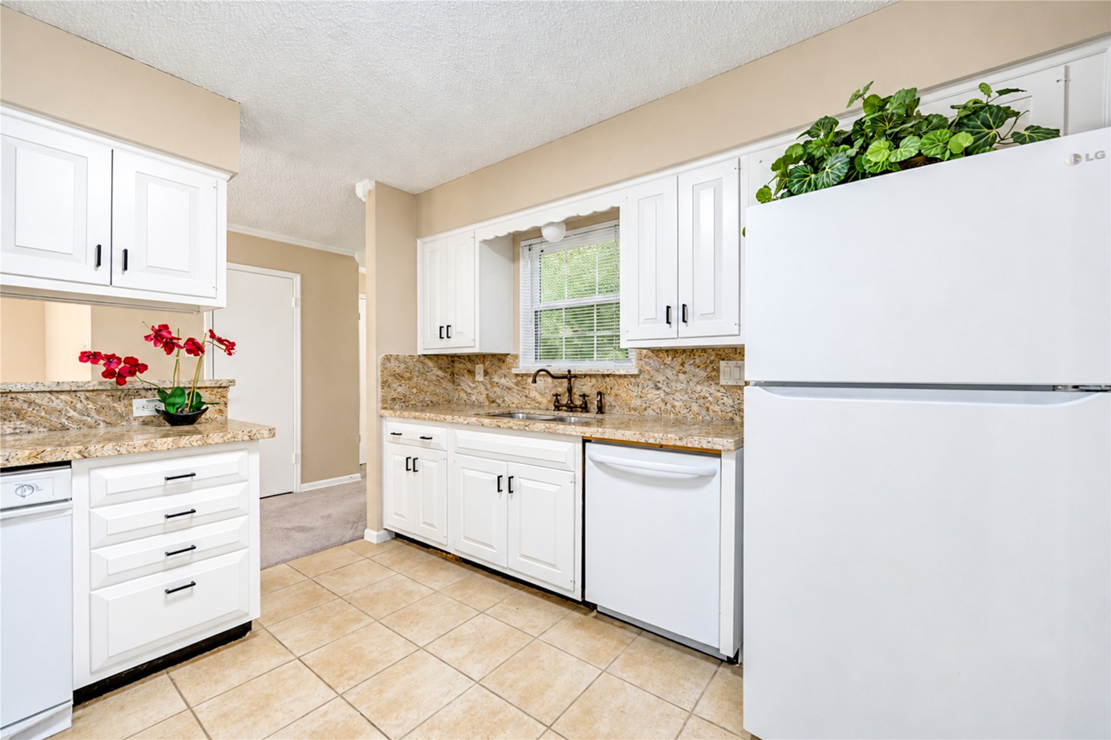 Bright kitchen with elegant granite countertops, white cabinetry, and modern appliances, offering a clean and inviting space for cooking and entertaining.