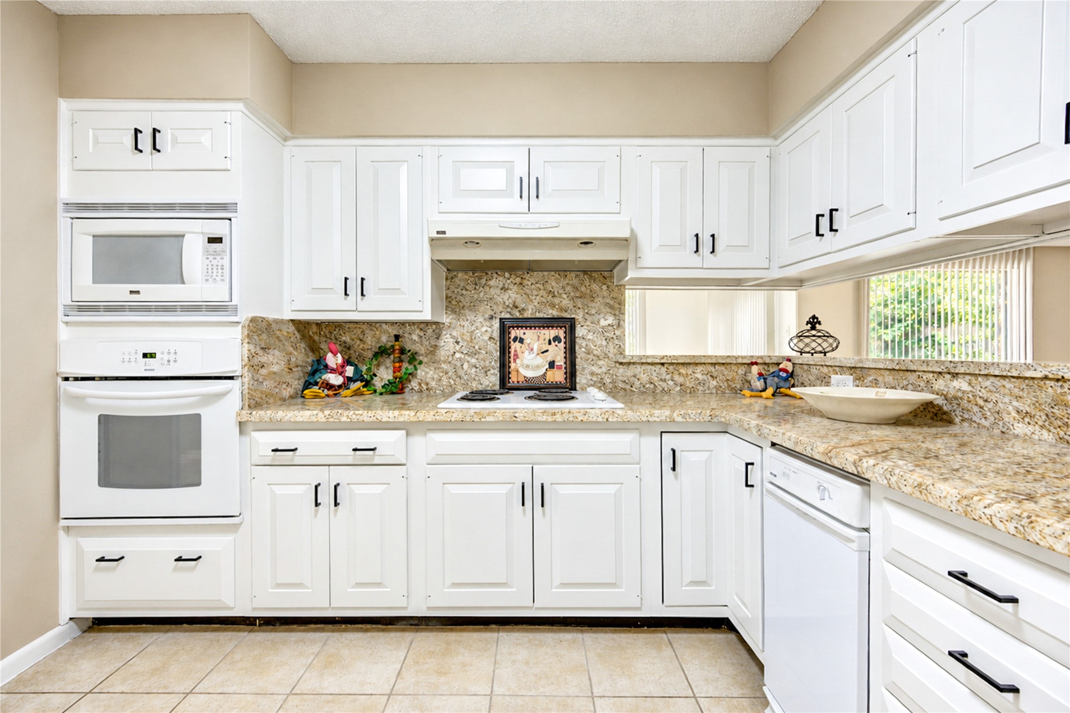 Bright, modern kitchen featuring elegant white cabinetry, granite countertops, and built-in appliances for a sleek, functional space.