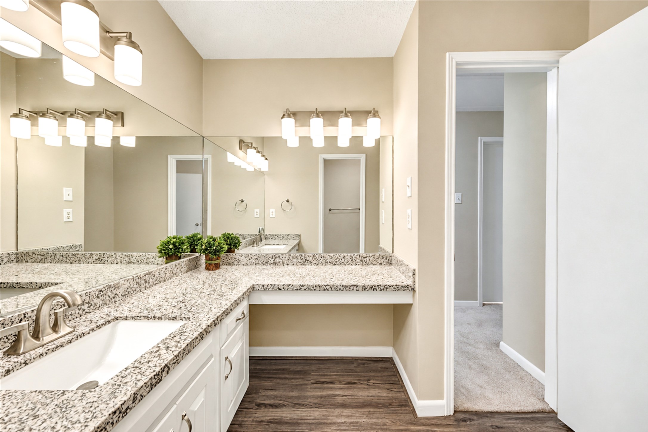 Elegant secondary bathroom featuring a granite countertop with dual sinks, stylish lighting fixtures, and ample storage in a serene, neutral color palette.