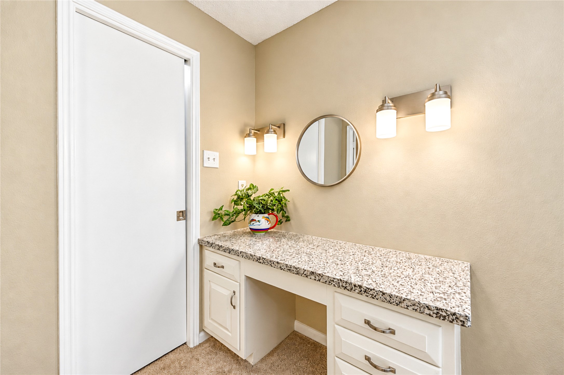 Charming vanity area with a sleek granite countertop, ample drawer storage, and elegant lighting, perfect for a personal retreat.
