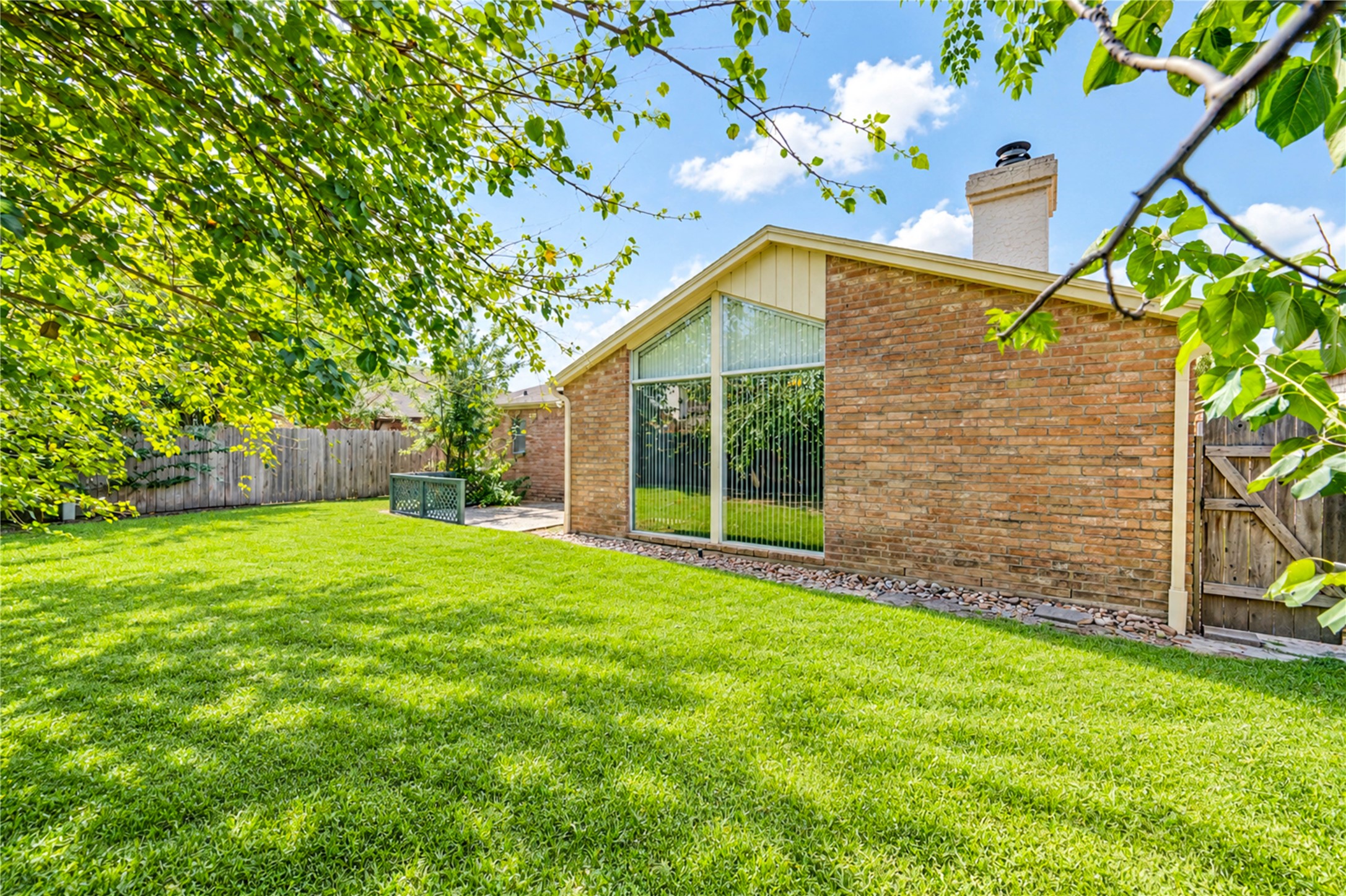 Expansive backyard with lush green lawn and a charming brick exterior, perfect for outdoor activities and relaxation.