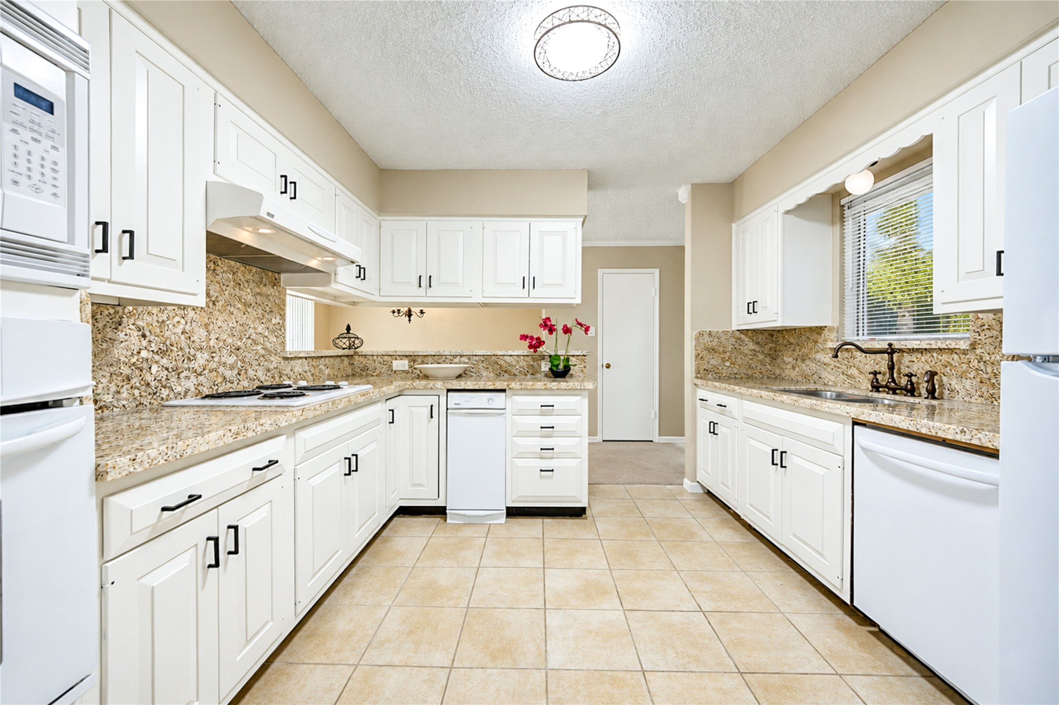 Charming kitchen with elegant white cabinetry, granite countertops, and modern appliances, complemented by ample natural light and a cozy atmosphere.