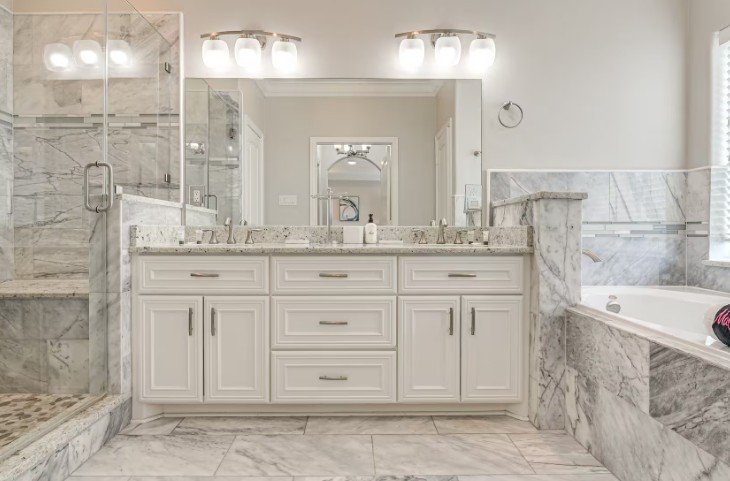 Luxurious primary bathroom featuring elegant marble finishes, a spacious glass-enclosed shower, dual sinks with sleek fixtures, and a relaxing soaking tub.