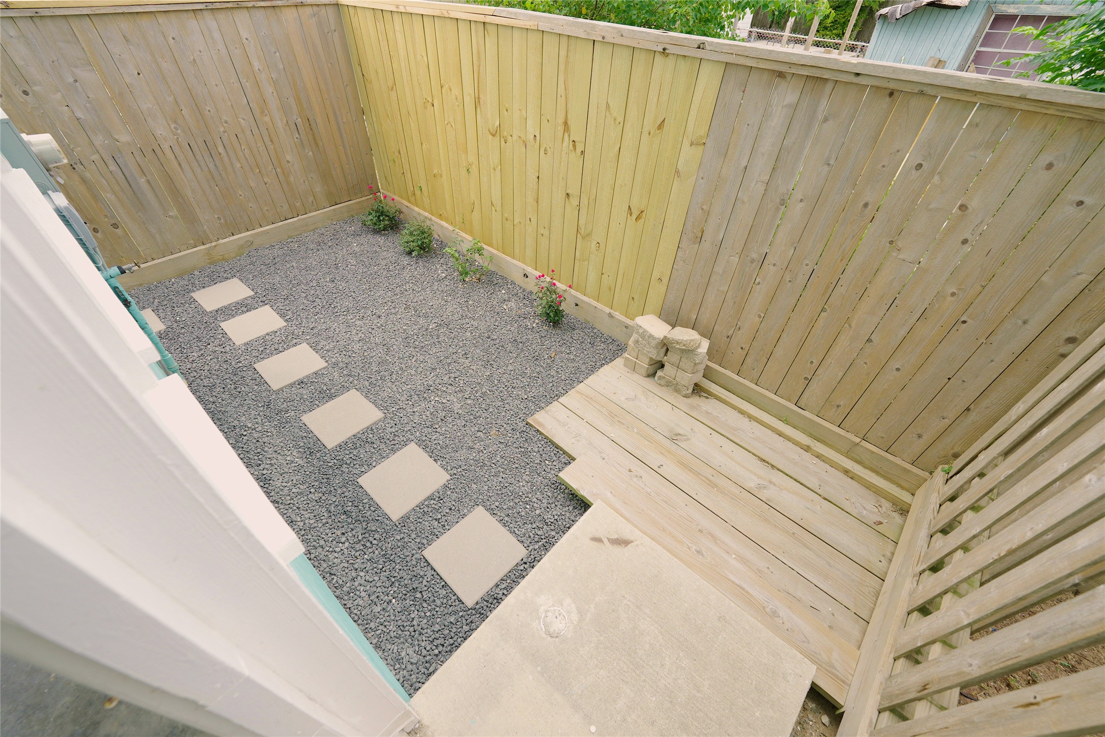 Charming back porch with a private, fenced-in area featuring a low-maintenance gravel path and cozy wooden deck, perfect for relaxation.
