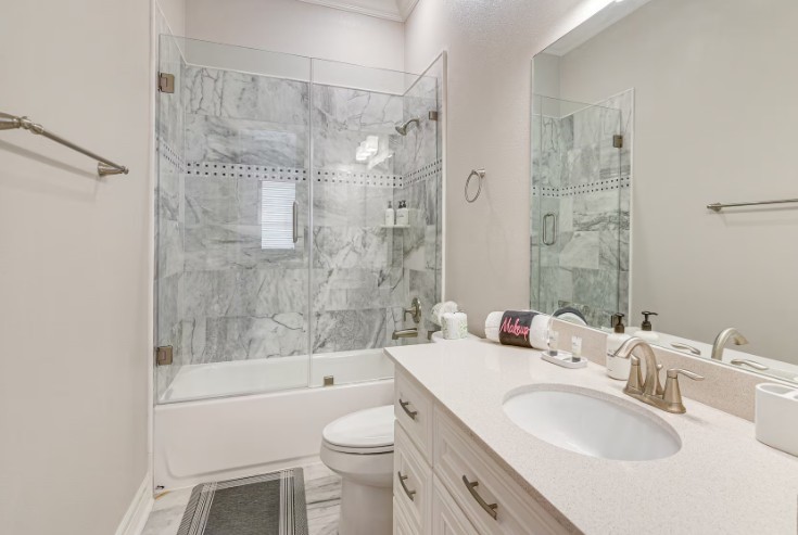 Elegant guest bathroom featuring a sleek glass-enclosed shower, sophisticated marble tile, and a modern vanity for a touch of luxury.