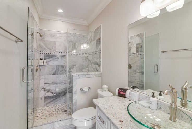 Elegant guest bathroom featuring a sleek glass-enclosed shower, luxurious marble tile, and modern fixtures for a touch of sophistication.