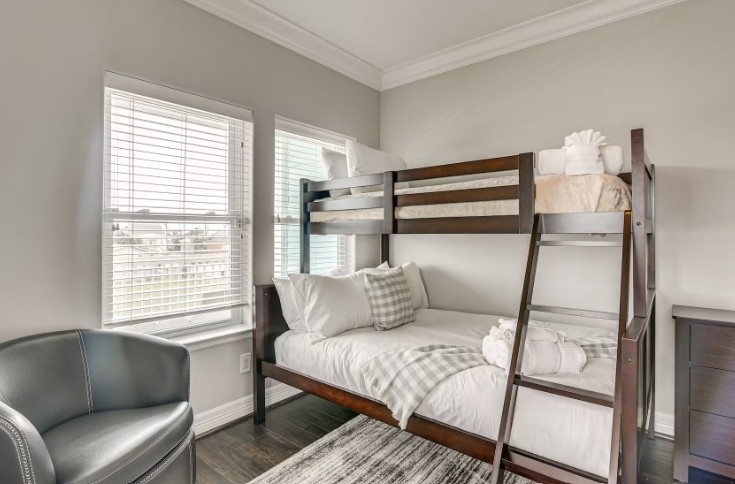 Elegant top-level guest bedroom, fully furnished with cozy twin bunk beds and abundant natural light.