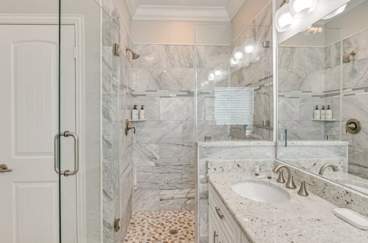 Luxurious primary bathroom featuring elegant marble finishes, a spacious glass-enclosed shower, and modern fixtures for a spa-like retreat.