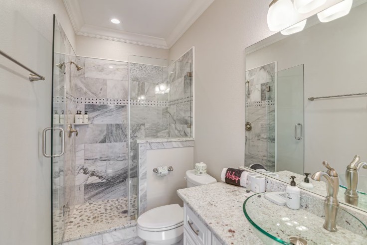 Elegant guest bathroom featuring a luxurious marble shower, modern fixtures, and a chic glass sink for a spa-like retreat.