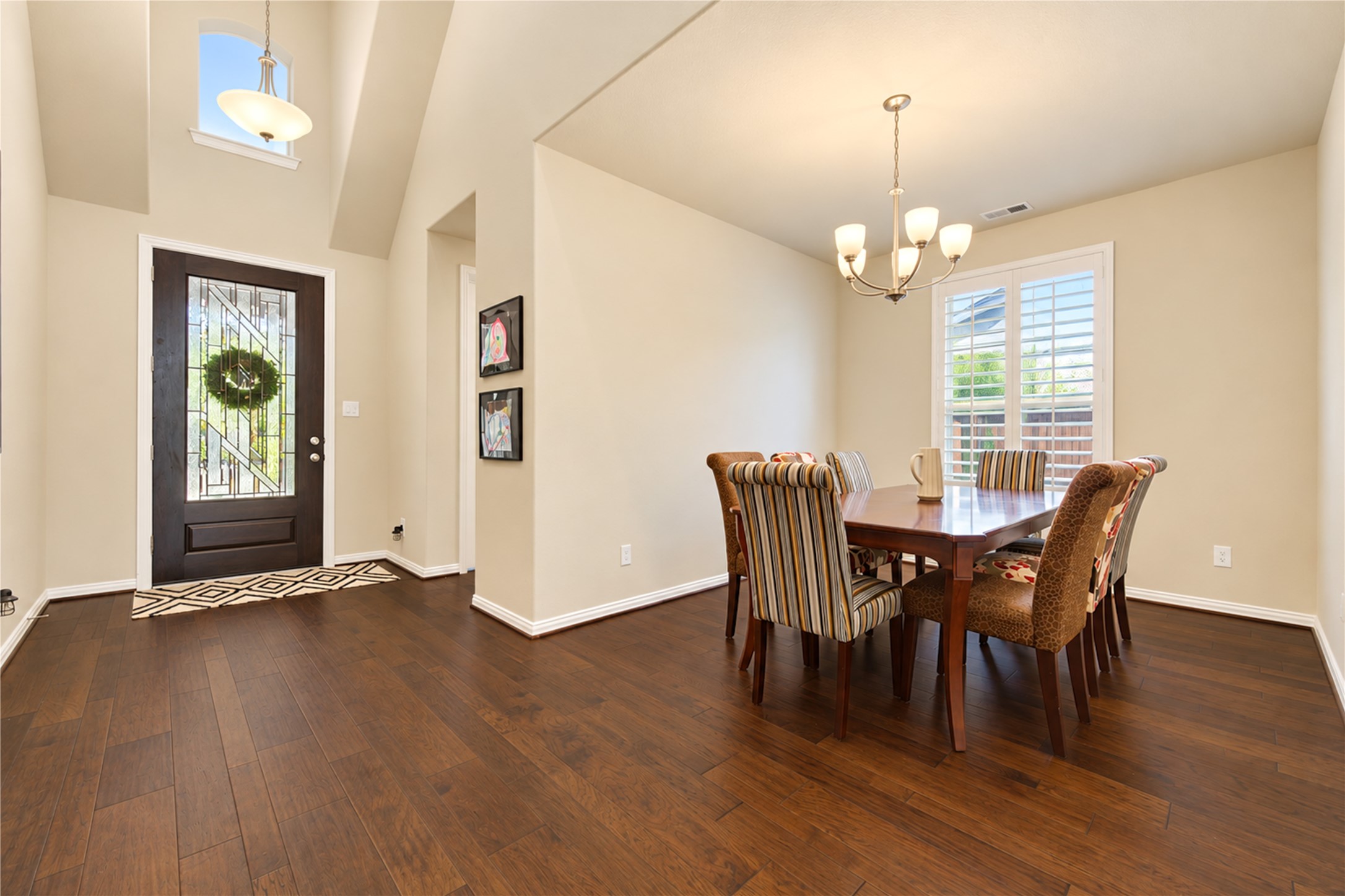 The homes impressive two-story entryway makes a grand first impression, featuring warm wood flooring and an elegant glass-and-wood front door that welcomes you inside.