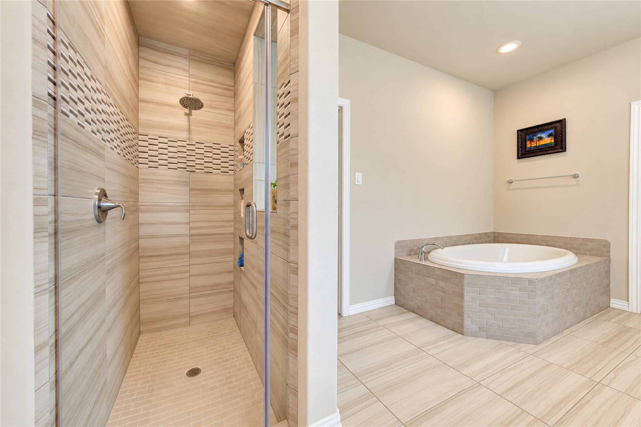 The spacious primary bath features a relaxing soaking tub, a walk-in tile shower, generous vanity space, and dual sinks, creating a comfortable retreat for everyday living.