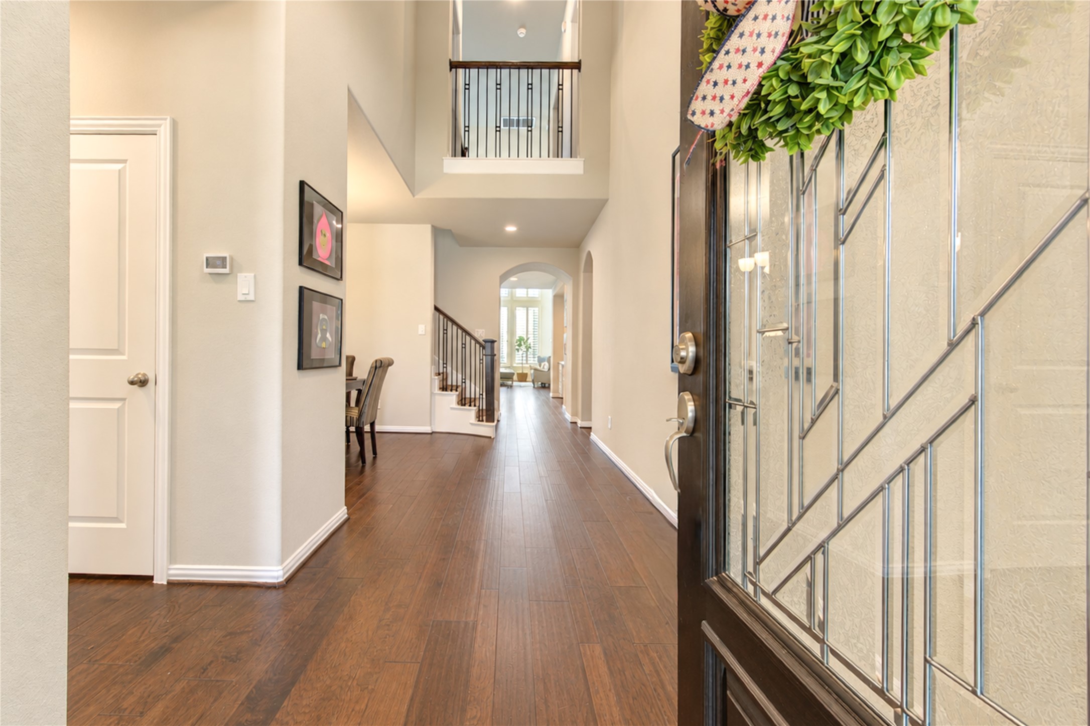 The homes impressive two-story entryway makes a grand first impression, featuring warm wood flooring and an elegant glass-and-wood front door that welcomes you inside.