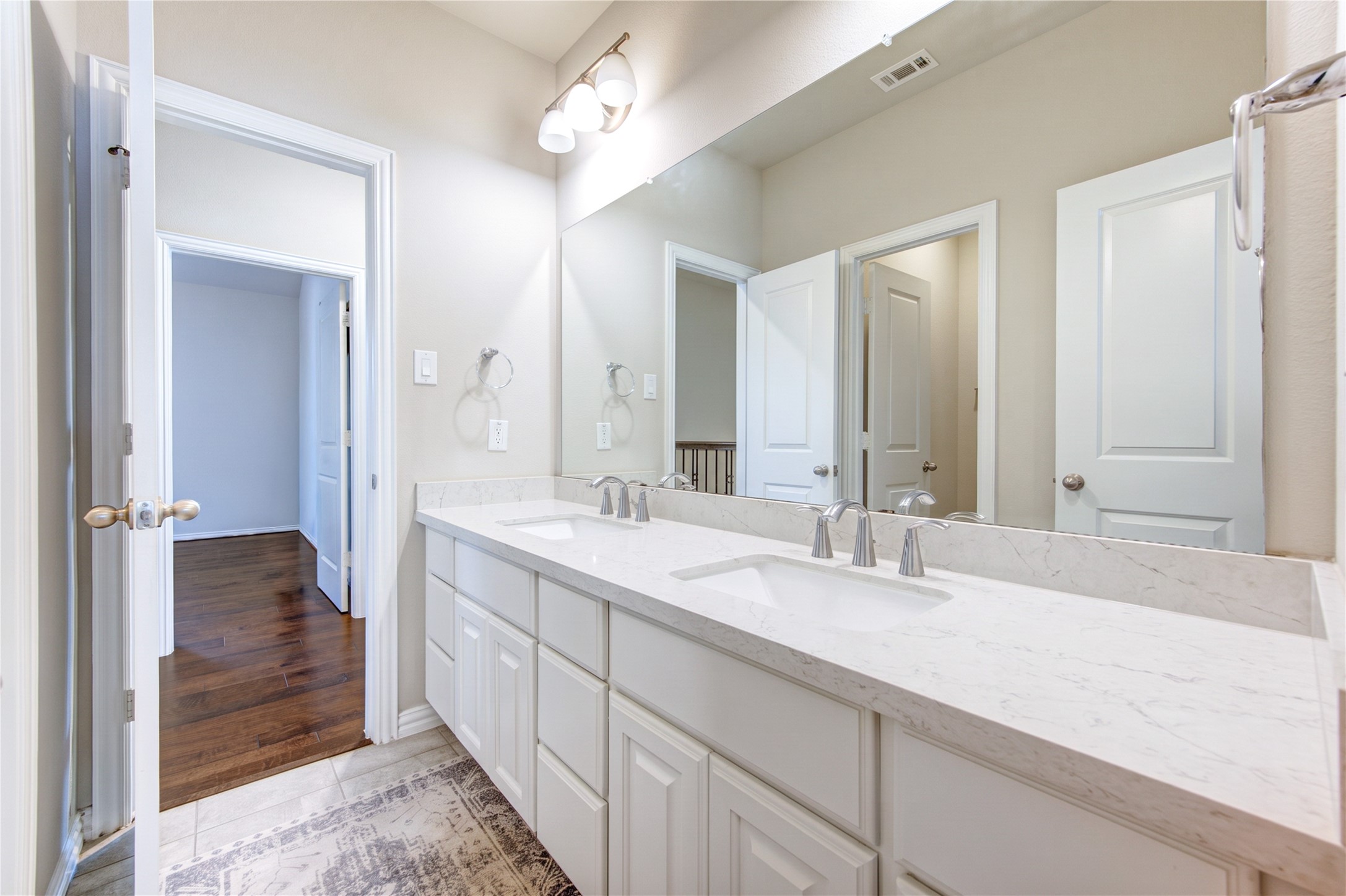 The upstairs bathroom features a dual-sink vanity and a tile-surround tub and shower combination, offering both style and functionality for family and guests.