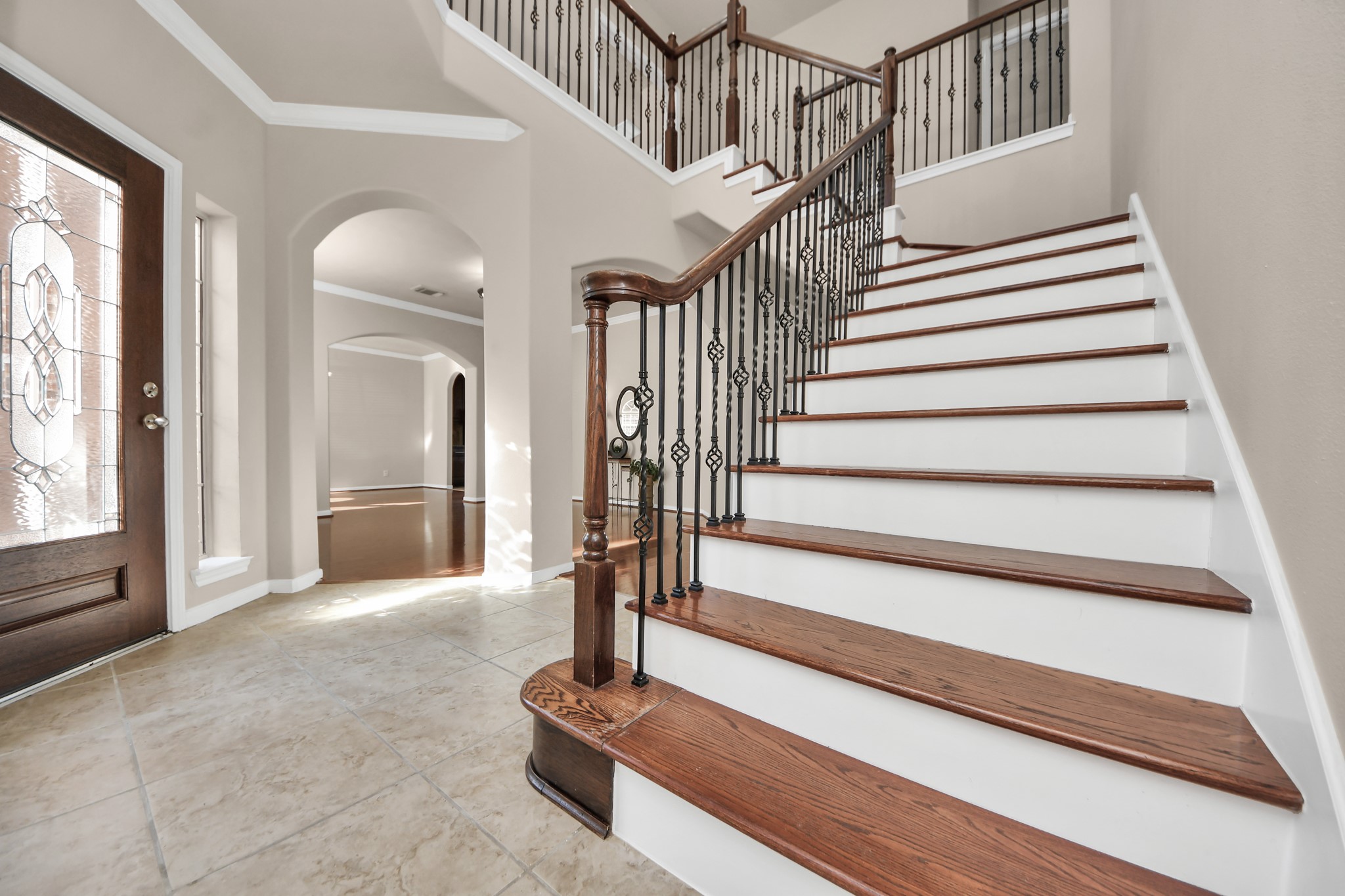 Featuring pristine white risers and sophisticated wrought iron balusters, this striking staircase serves as a luxurious focal point immediately upon entering the home.
