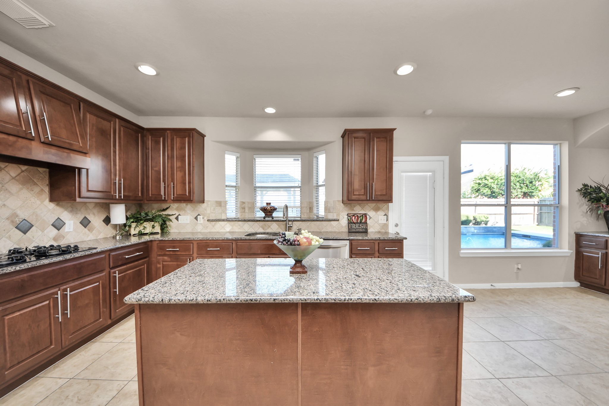 The kitchen features generous counter space, abundant storage, two walk-in pantries, and beautiful views of the pool.