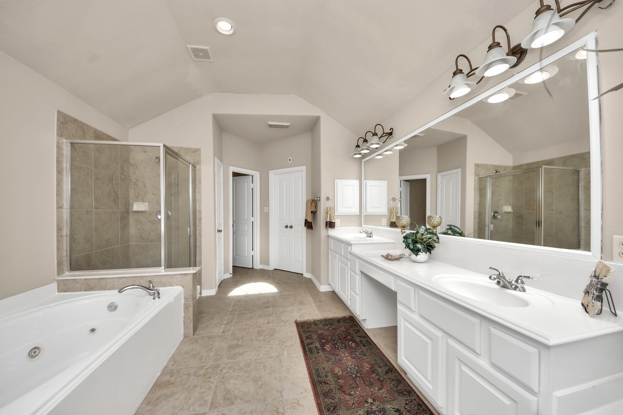 This bathroom features high ceilings, double sinks, and a vanity, providing a complete and functional space.