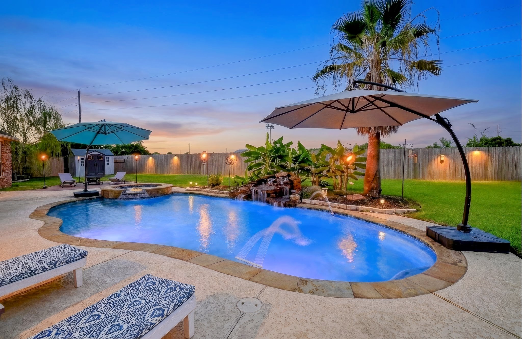The sparkling freeform pool with a waterfall has a Pebbletec surface and an in ground cleaning system.