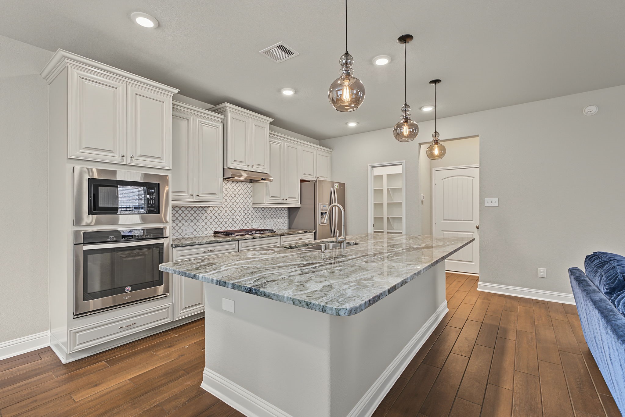 A view of the kitchen, walk in pantry and drop zone just off the garage entry.