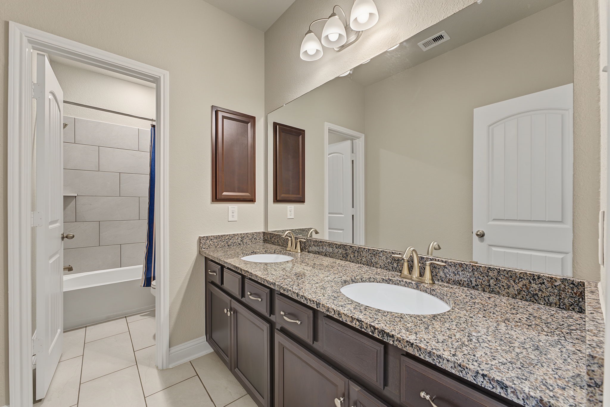 The secondary bathroom features double sinks, an expansive amount of counter space & storage. Notice the separate tub/shower and potty!