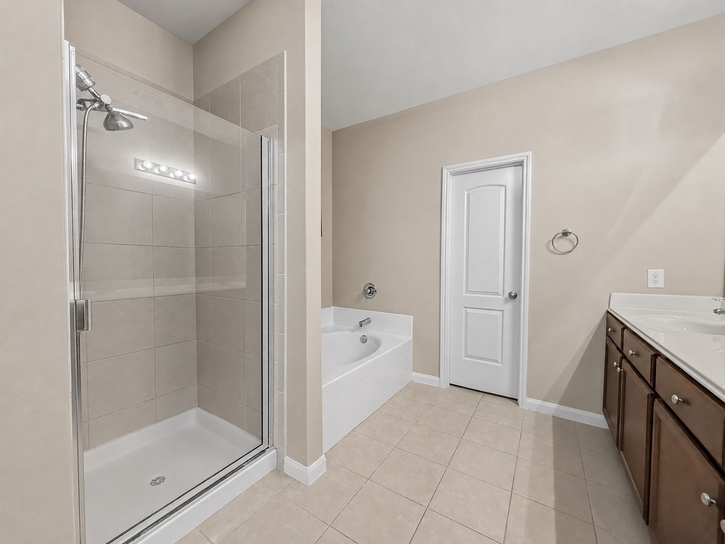 A separate walk-in shower and large soaking tub are both available. The door ahead leads to the Primary Suites huge walk-in closet.