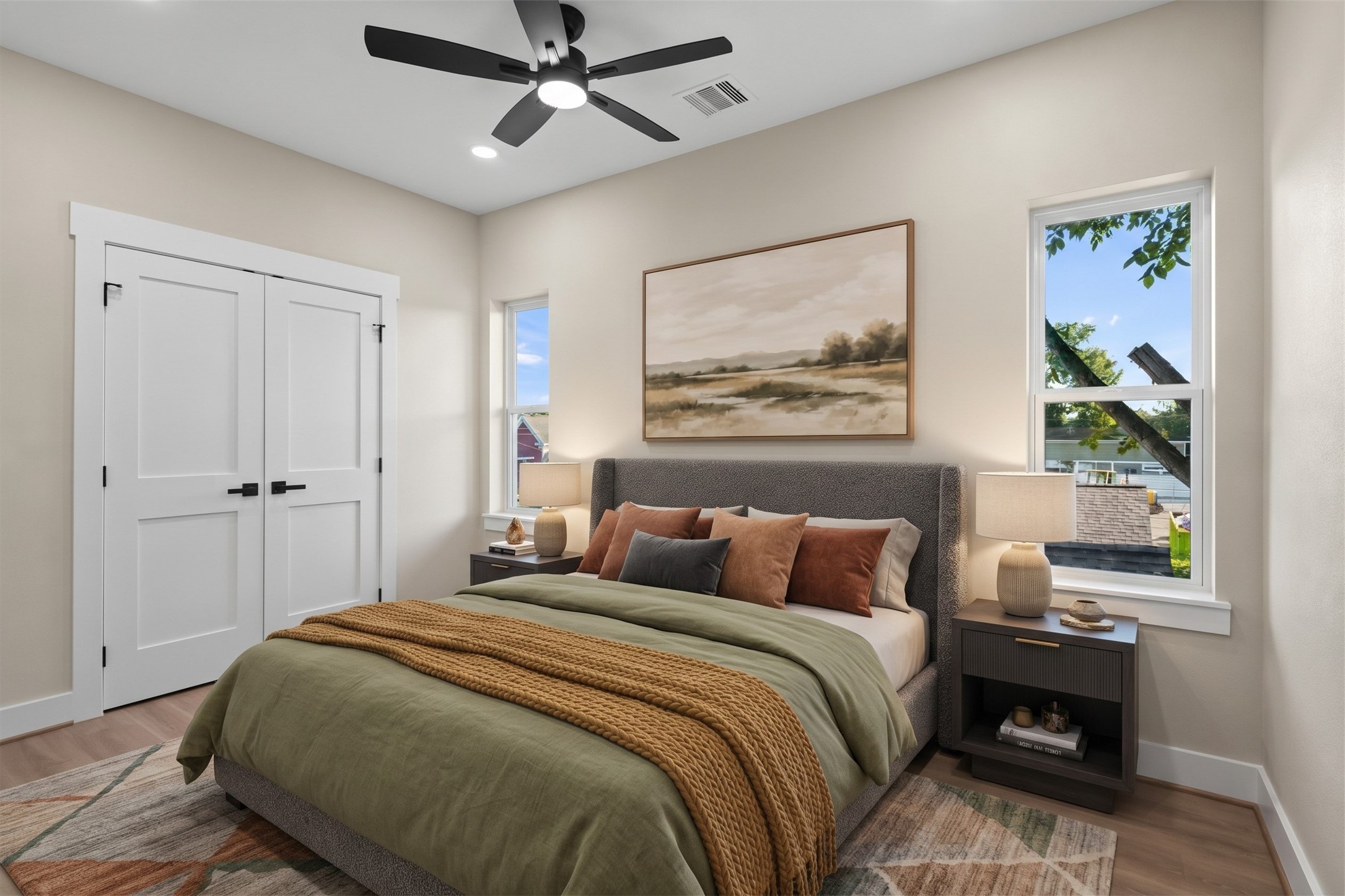 Virtually Staged: Blending clean design with smart utility, this bedroom offers an airy layout illuminated by multiple window placements. Elevated light fixtures and generous floor clearance make this room a practical, restful addition to the home.