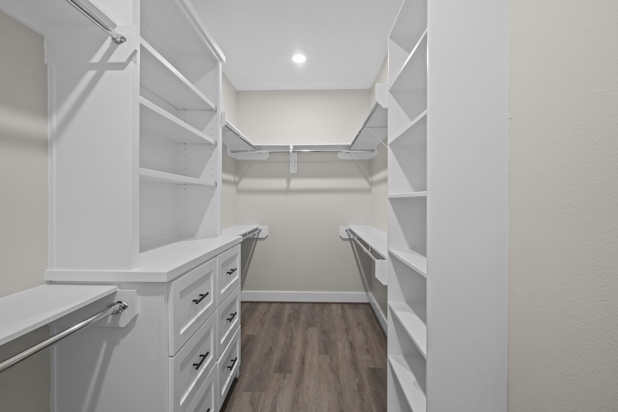 Designed for optimal wardrobe storage, this primary closet offers built-in chest-of-drawers, overhead shelving, and multi-tier hanging space.