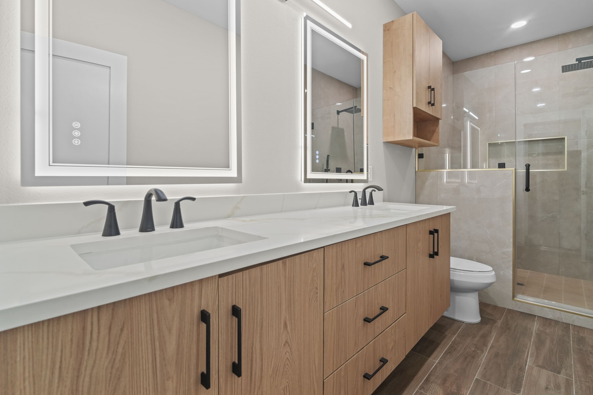 Modern functionality meets elevated design in this primary bath suite. Features include an elongated vanity layout with integrated lighting, dual sinks, and a walk-in glass shower.