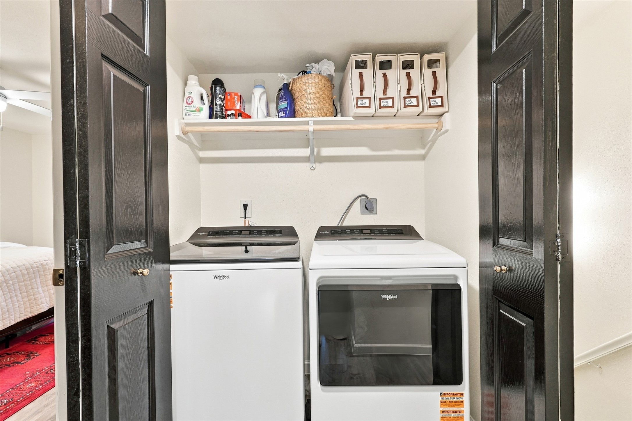 Convenient laundry area with modern Whirlpool washer and dryer, neatly tucked behind sleek black doors, offering efficient and stylish functionality.