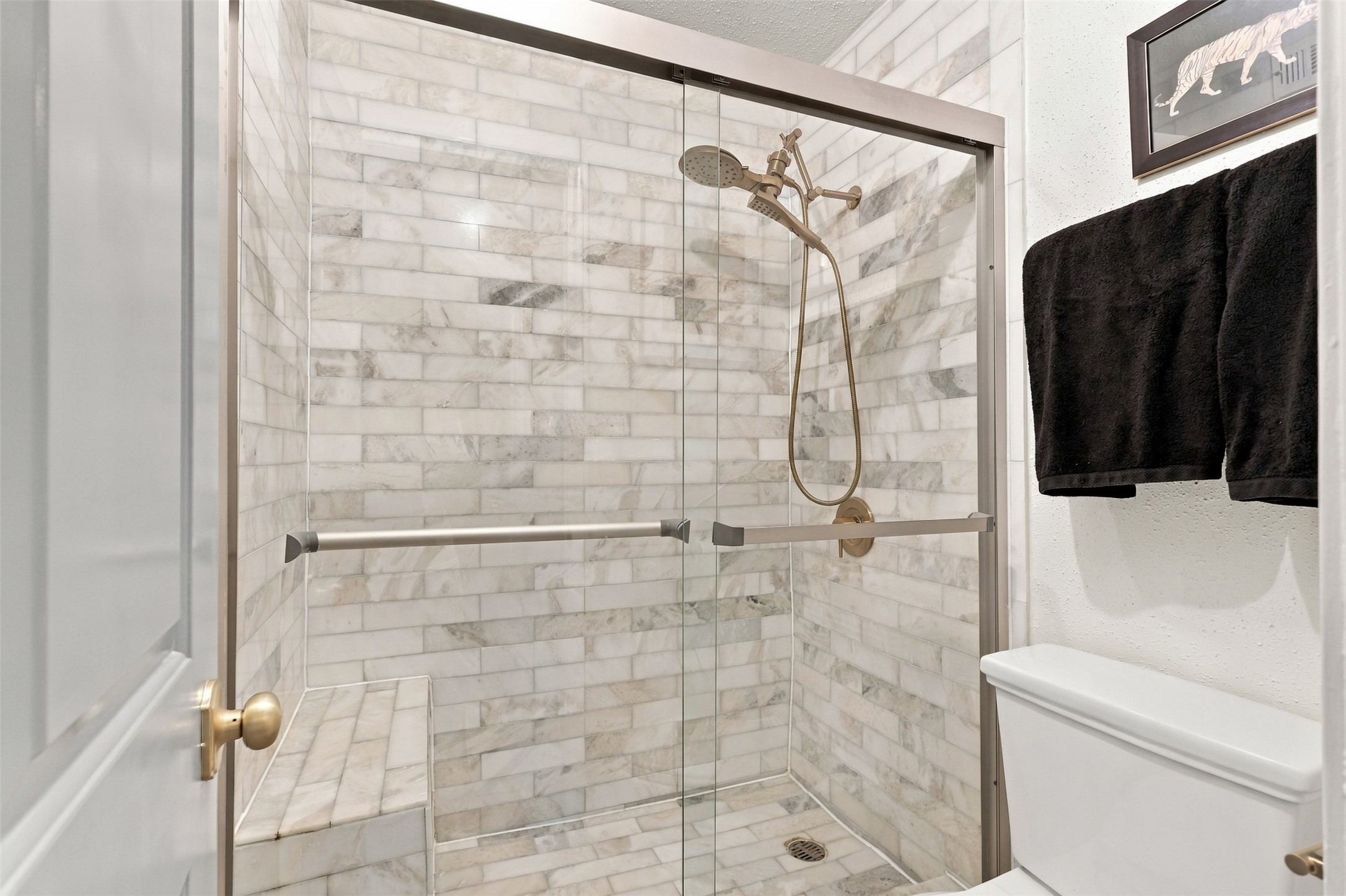 Elegant bathroom featuring a spacious walk-in shower with stylish marble tile and a sleek glass door, complemented by modern fixtures.