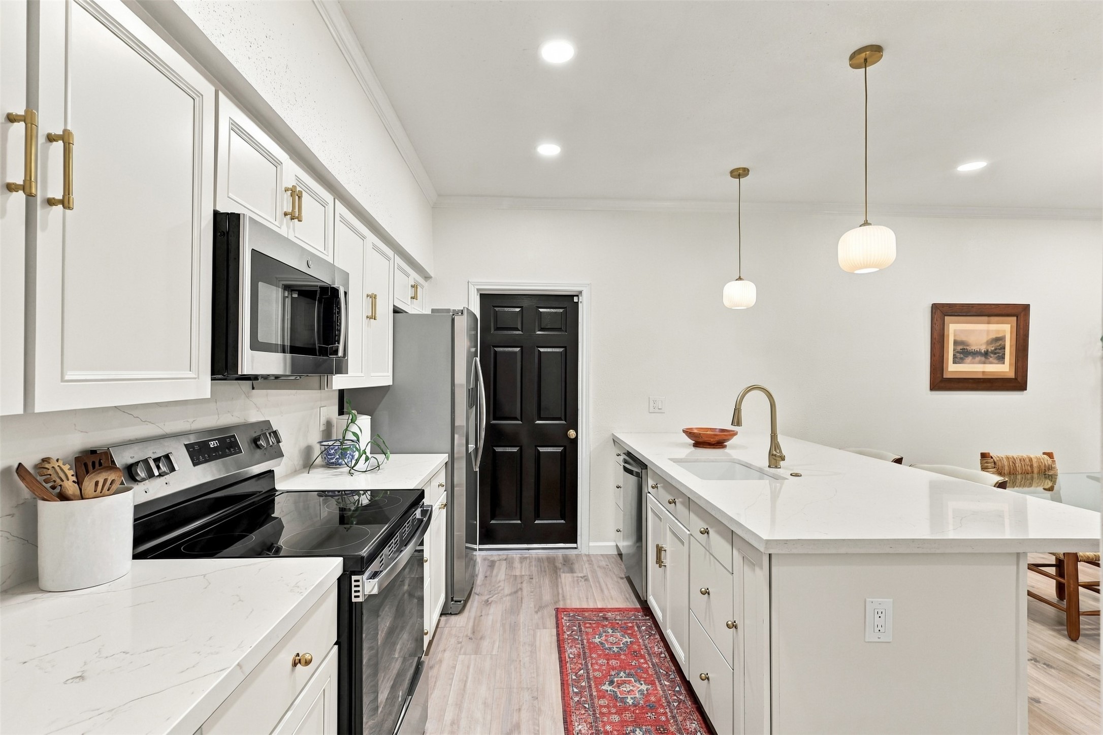 Modern kitchen with sleek white cabinetry, stainless steel appliances, and a spacious island featuring elegant pendant lighting.