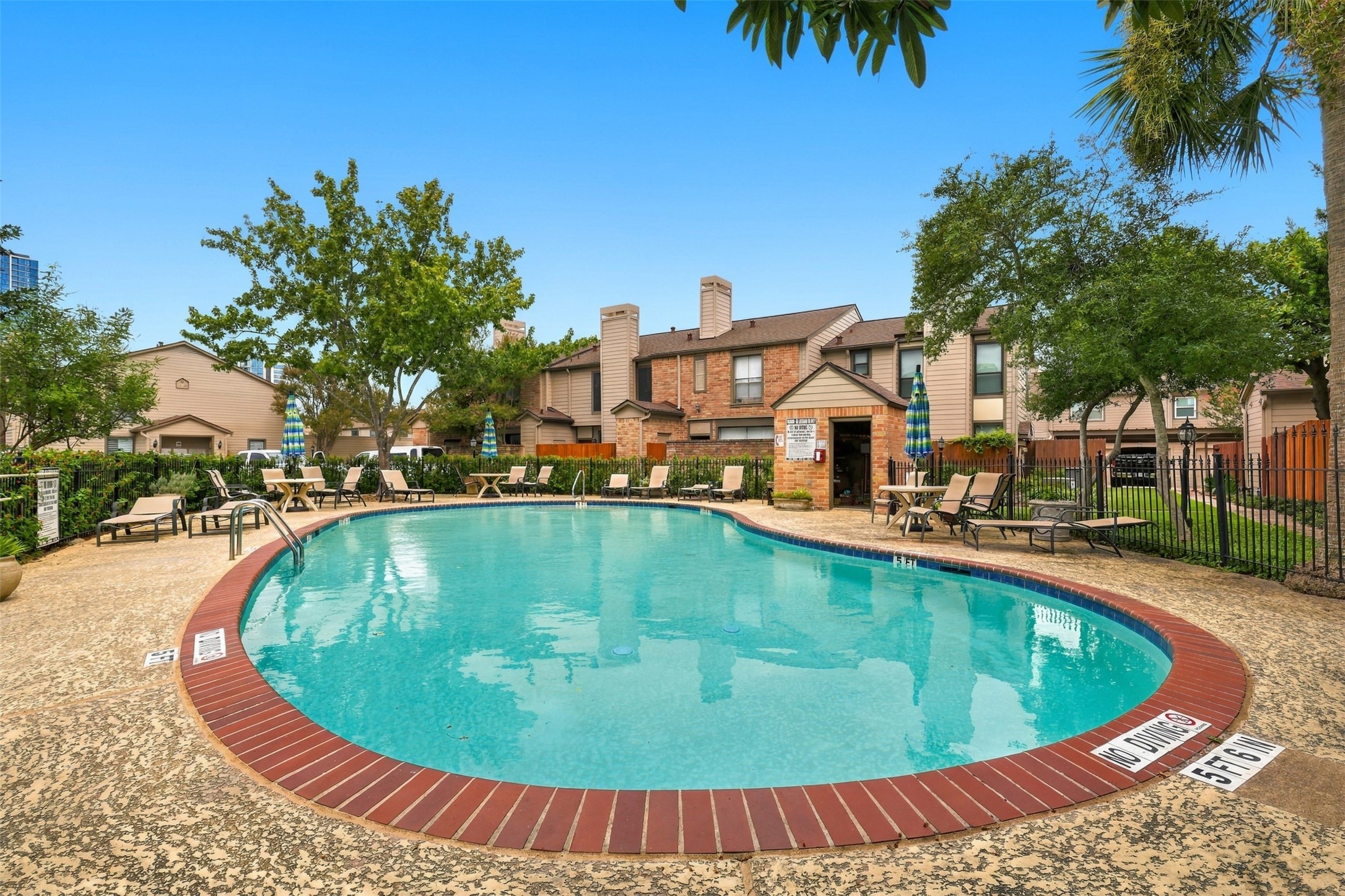 Relax by the sparkling community pool, surrounded by lush greenery and comfortable lounge seating, perfect for enjoying sunny days.