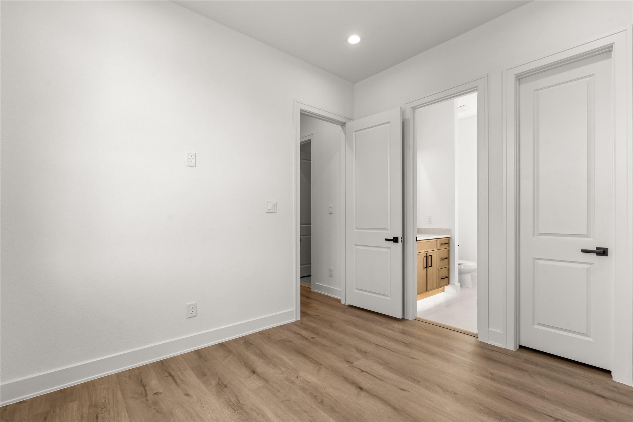Warm-toned flooring, crisp white finishes, and a functional layout create an inviting space that balances style with practicality.