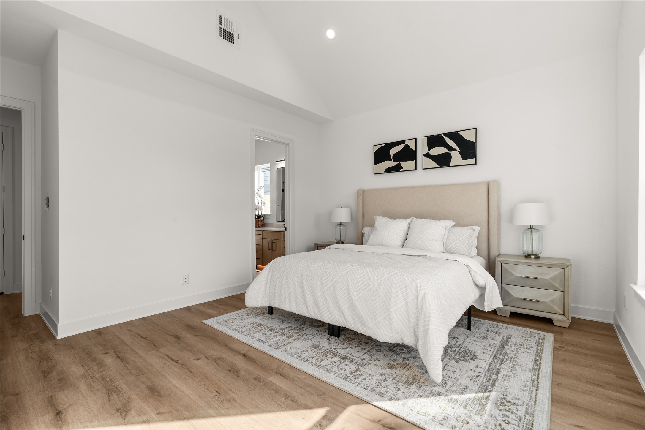 The primary suite's vaulted ceiling creates a dramatic sense of height, with its angular geometry lending architectural interest to an otherwise minimalist interior.