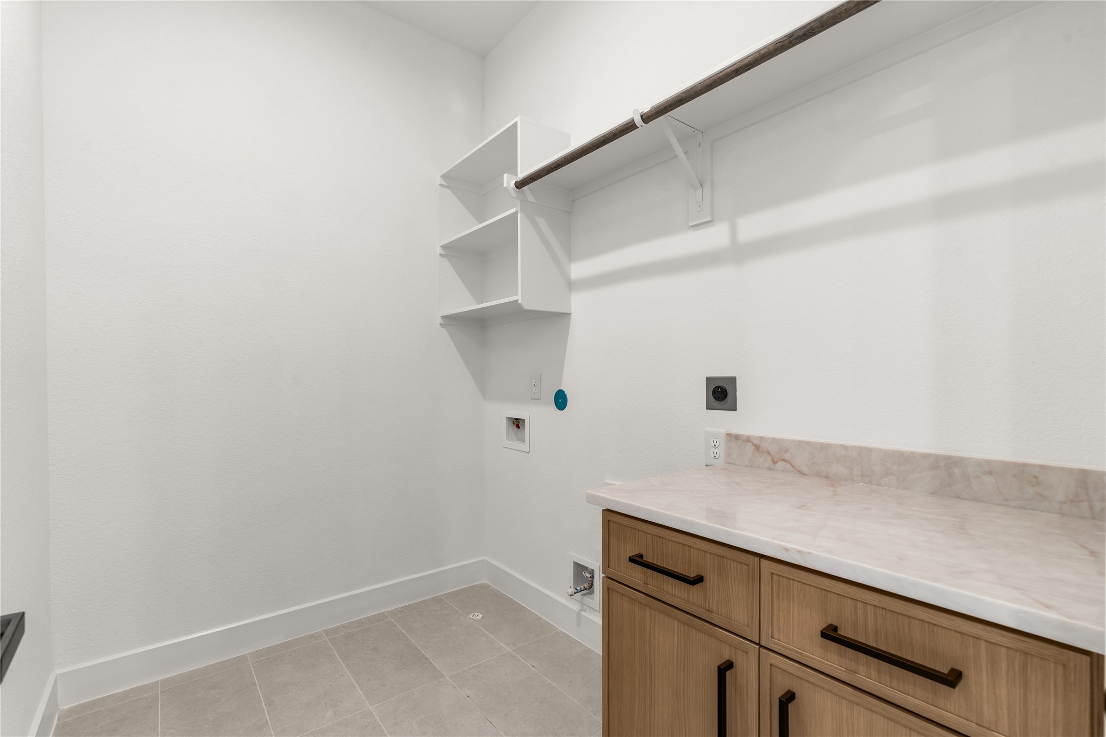 A thoughtfully designed utility room with a generous countertop and open shelving provide an organized setting for laundry and everyday household tasks.