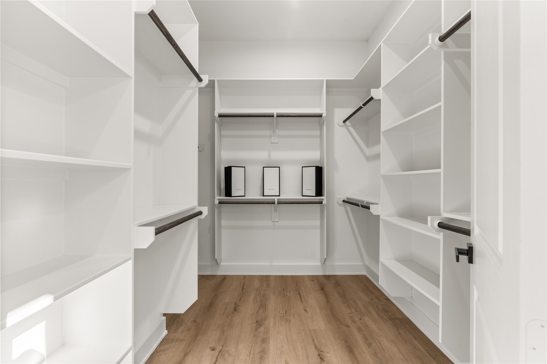 A well-appointed walk-in closet completes the primary suite, offering generous storage through a combination of built-ins, open display shelving, and dual-level hanging space.