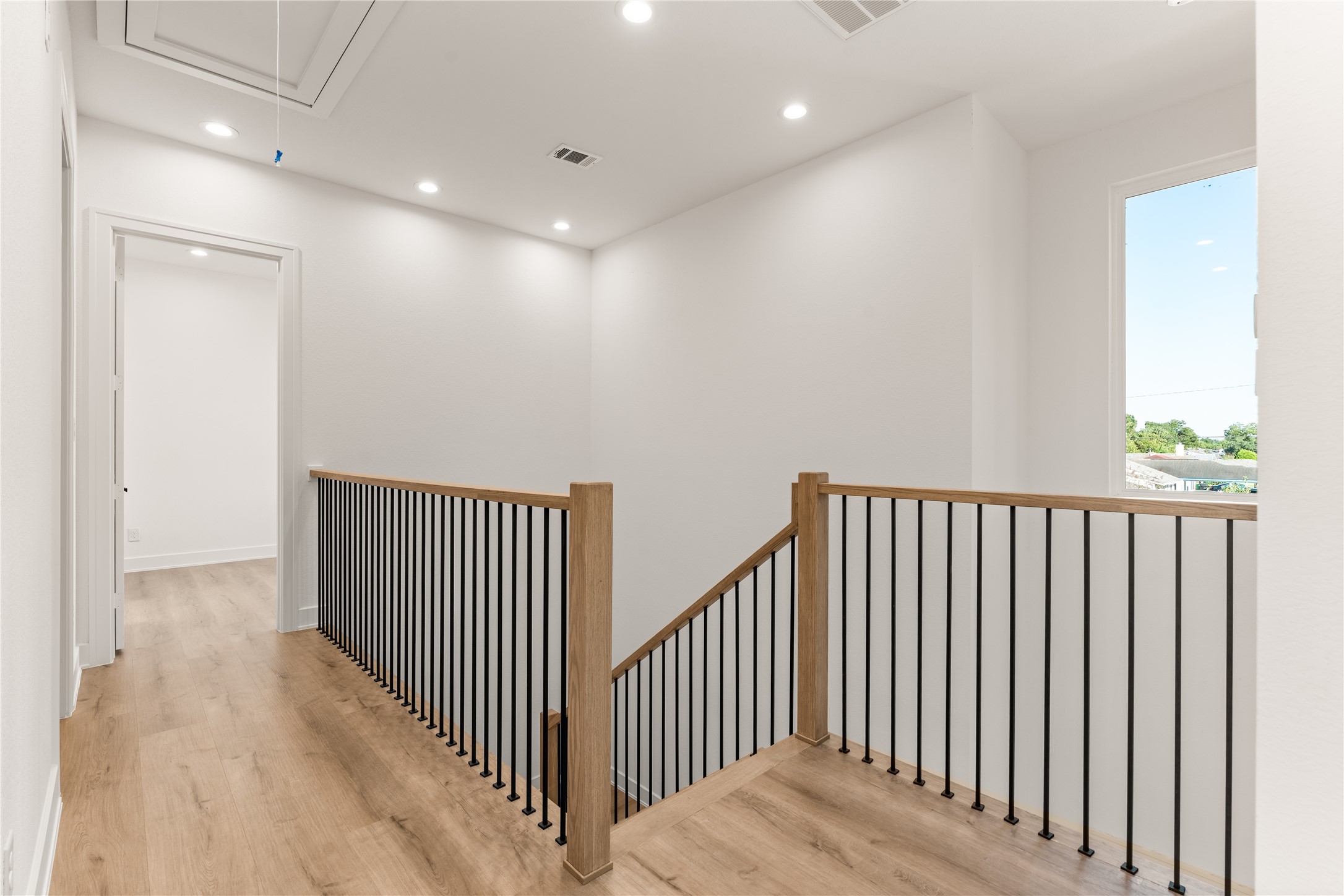 Light LVP flooring extends across the upper landing, while a large window introduces natural light and enhances the home's open, contemporary character.