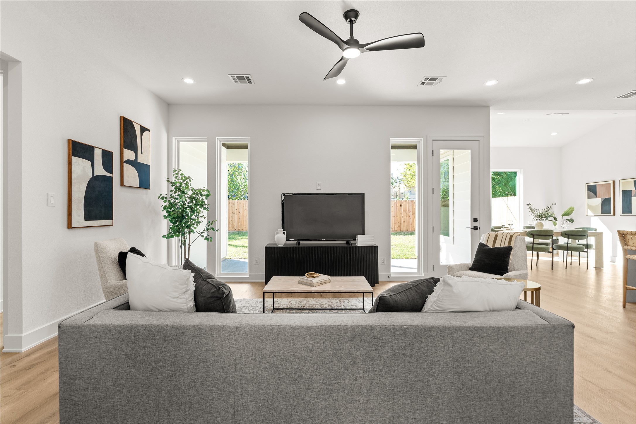Carefully positioned windows introduce a sense of rhythm and symmetry to the open concept living area, while an uninterrupted transition to the dining area enhances the home's cohesive design.