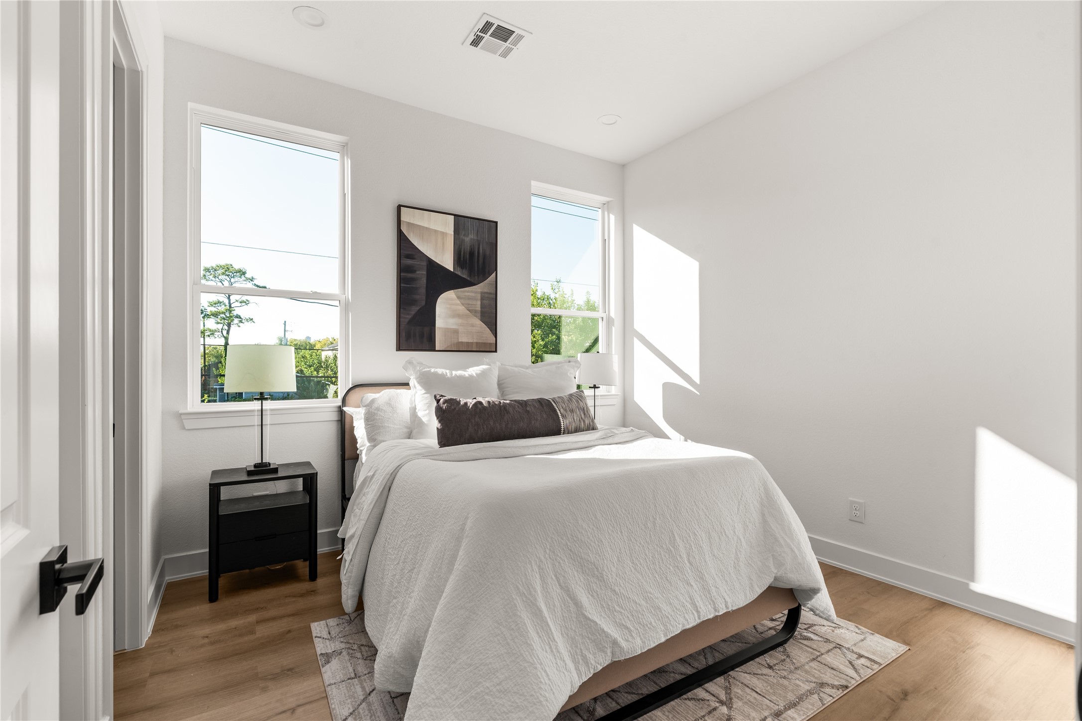 Sunlight pours through a pair of generously sized windows, lending an airy quality to this secondary bedroom.