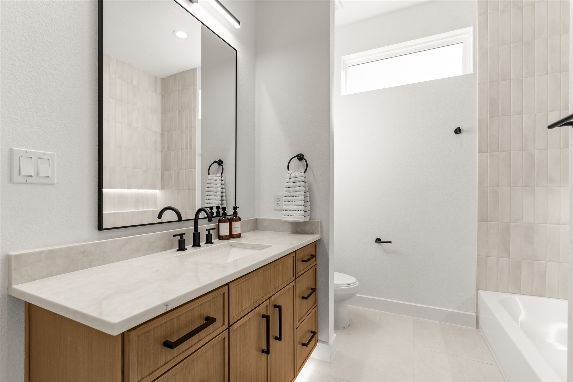 A cohesive selection of finishes defines this secondary bathroom, where understated materials create a polished yet welcoming atmosphere.