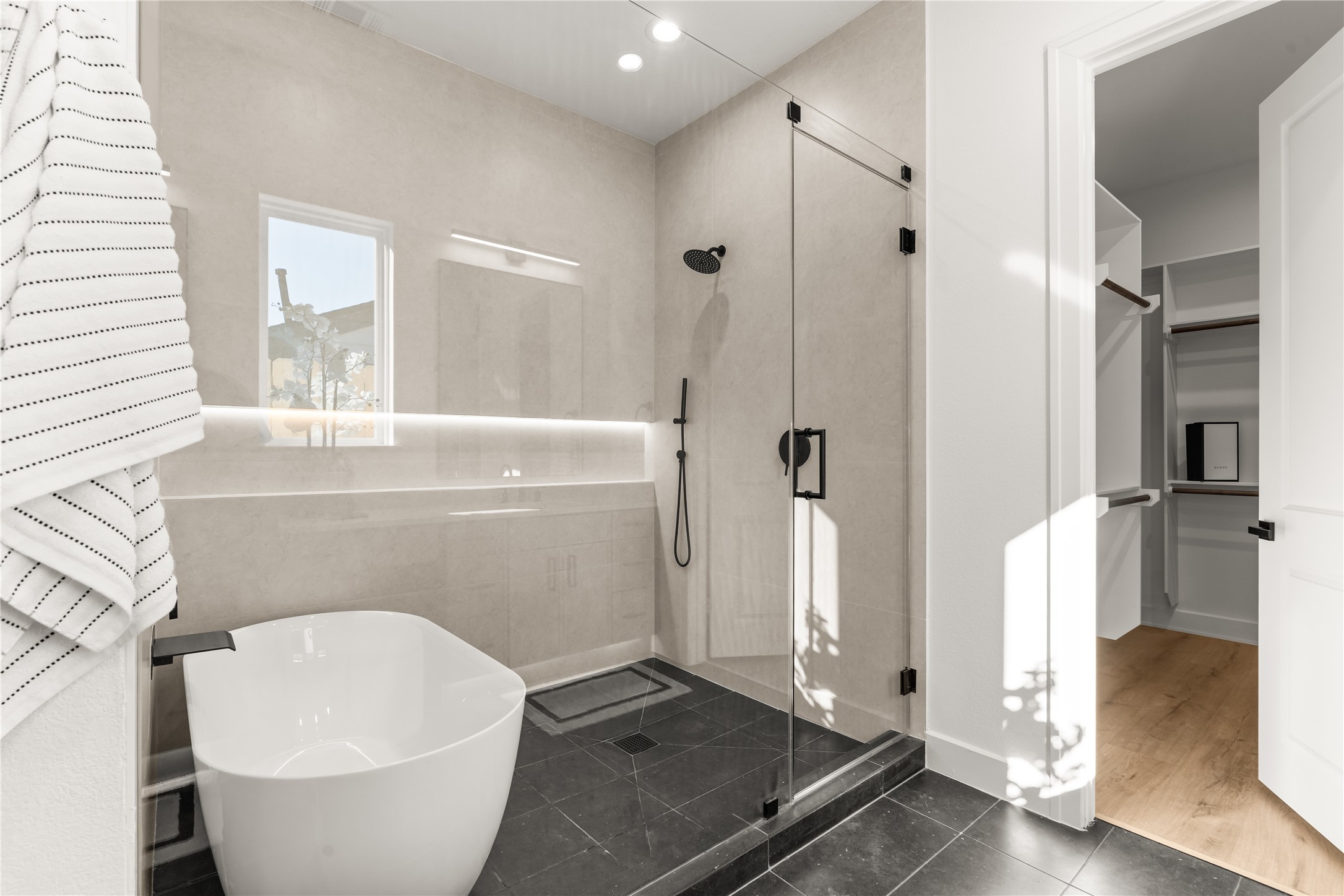 The primary ensuite balances contemporary design with spa-inspired comfort, featuring a freestanding soaking tub, an expansive glass-enclosed shower, and large-format tile.