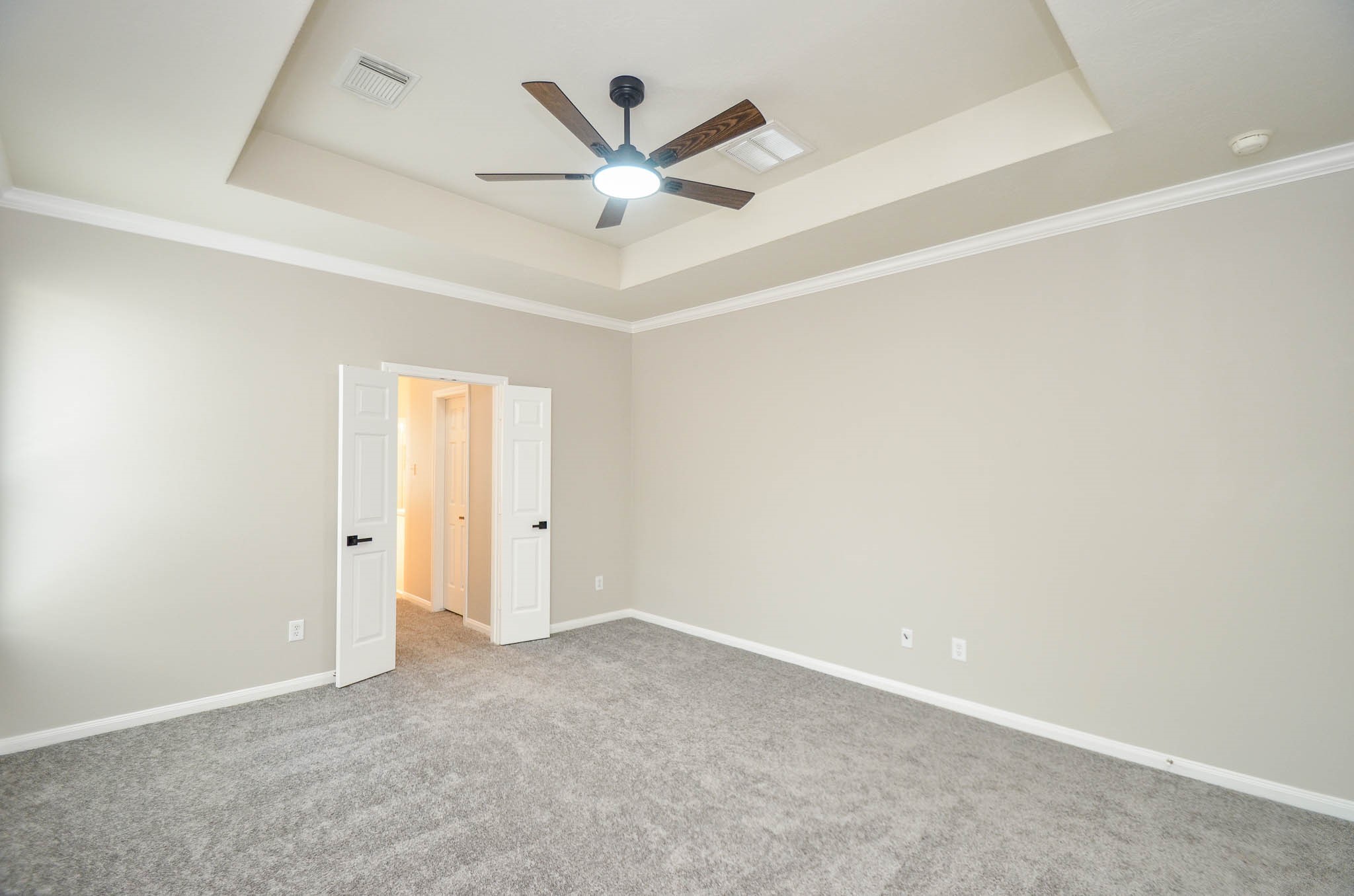 Primary suite without furniture... doors lead to bathroom