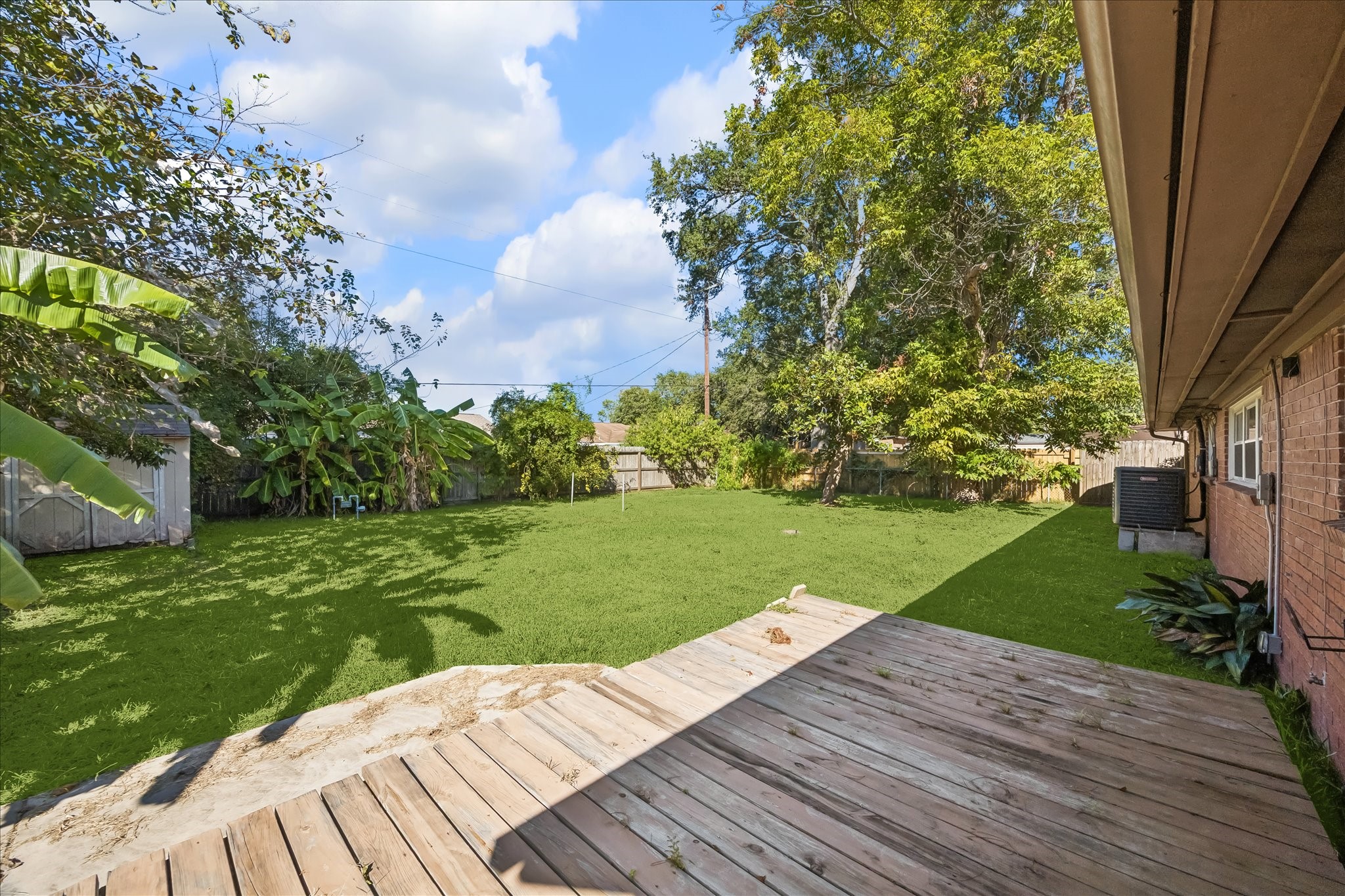 Wood deck overlooking the backyard with a storage shed.