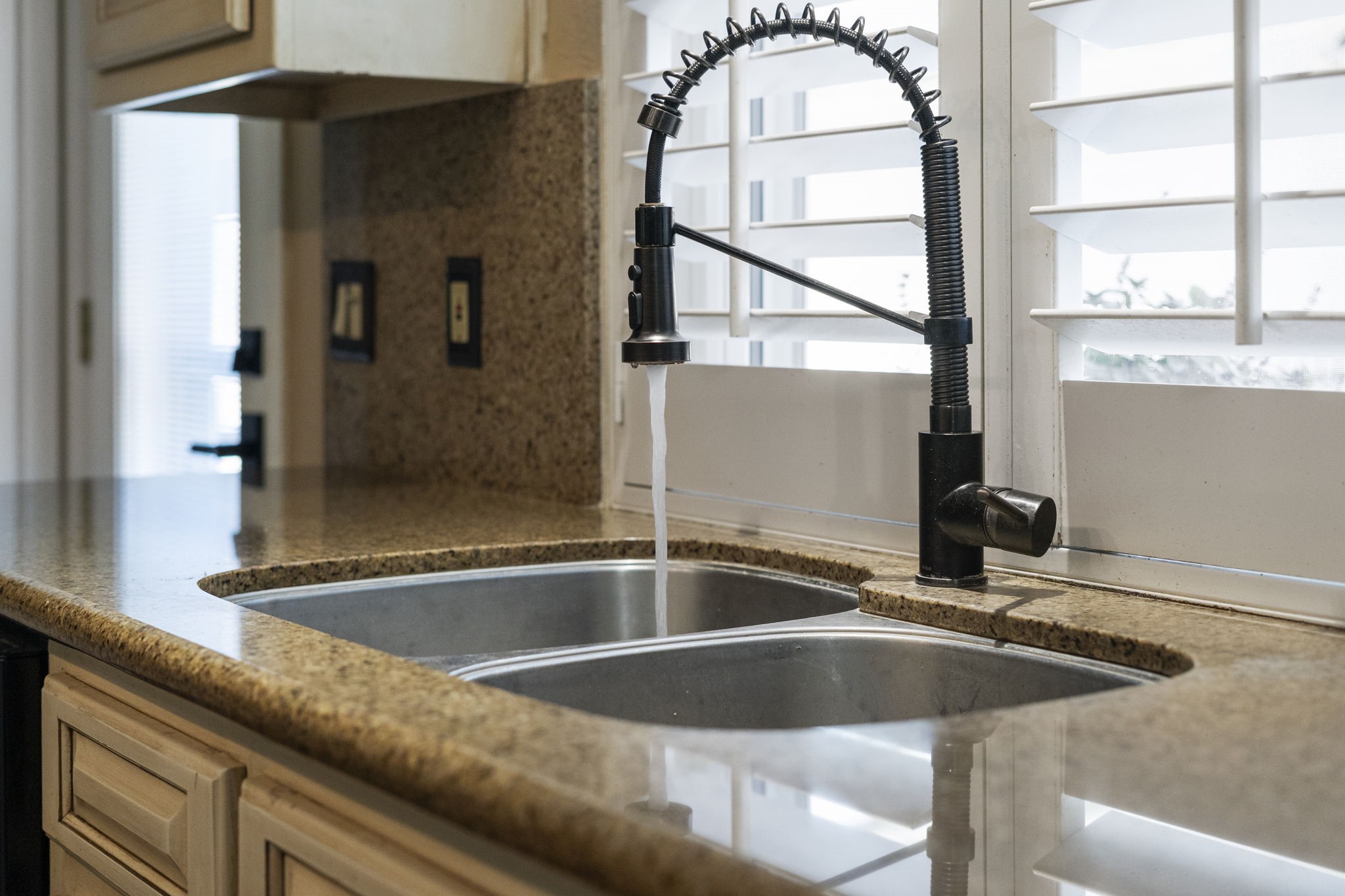 Double-basin stainless steel sink with a restaurant-style pull-down faucet, offering durability for everyday cooking and cleanup.