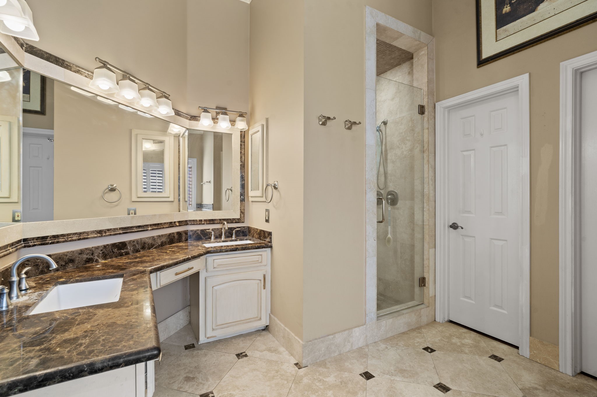 The bathroom also features dual vanities with stunning stone countertops and a spacious walk-in shower, along with two walk-in closets and a private water closet.